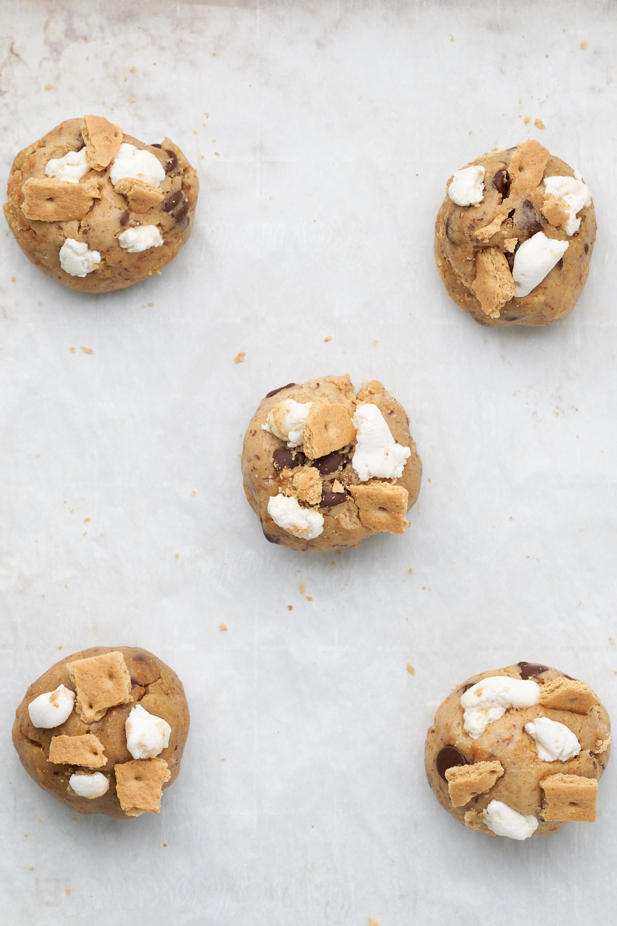 balls of cookie dough topped with marshmallows and graham crackers.