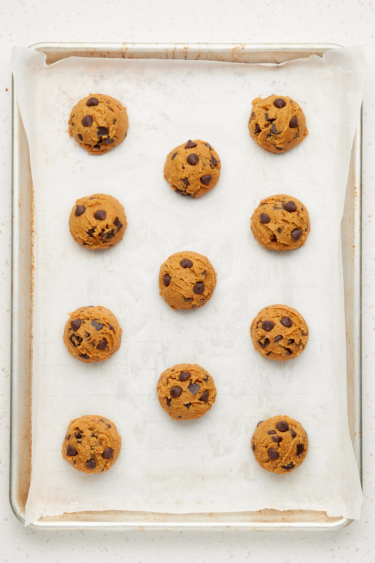 scoops of pumpkin chocolate chip cookie dough on a baking tray.