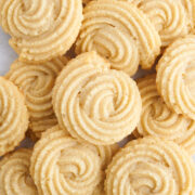 baked vegan butter cookies stacked on a baking tray.