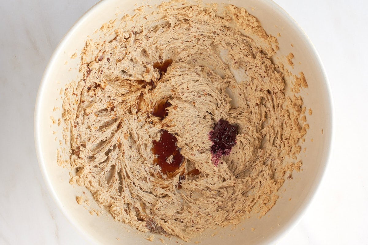 Creamed dairy-free butter and sugar in a bowl with vanilla and red food coloring added.