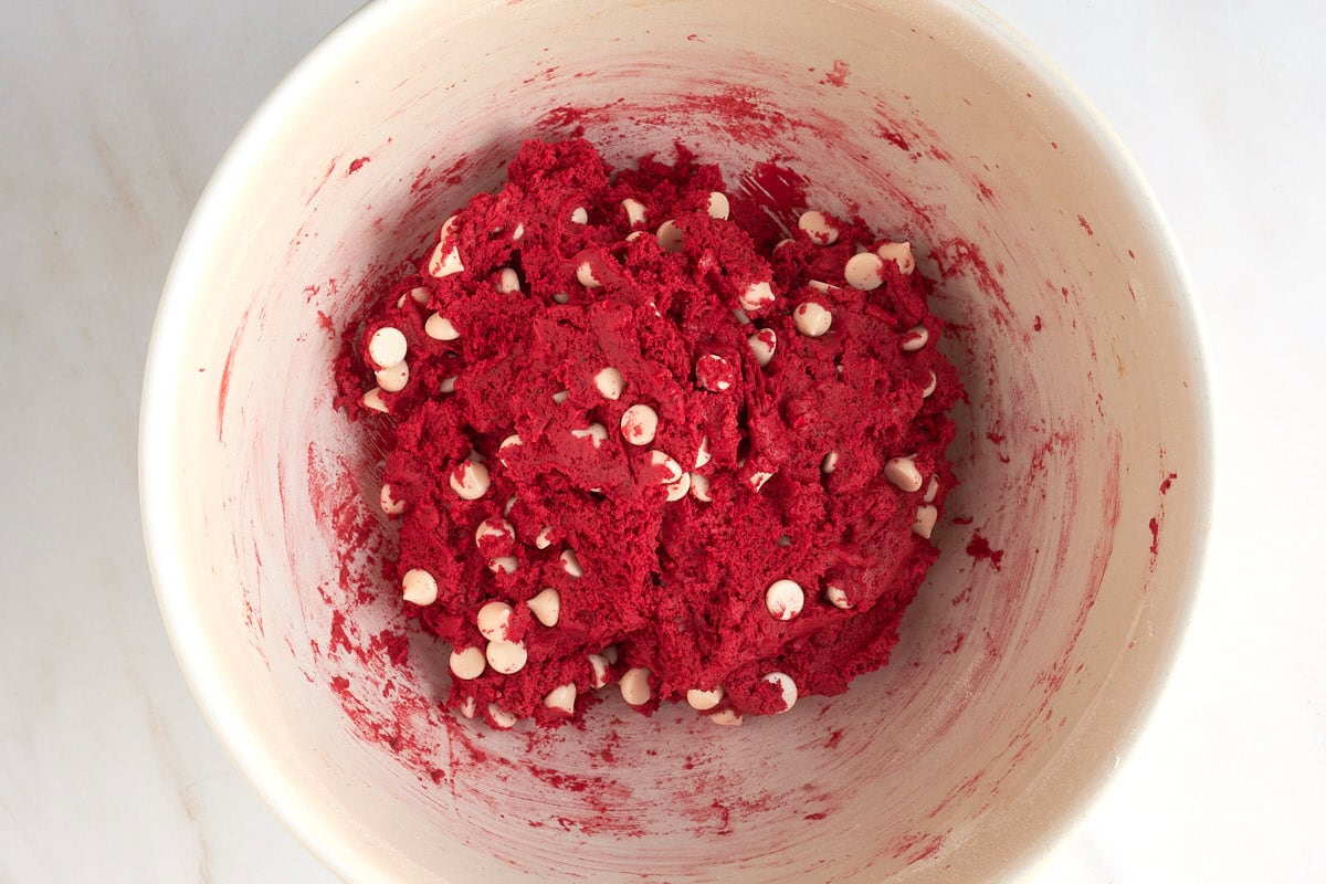 Red velvet cookie dough with white chocolate chips in a bowl.